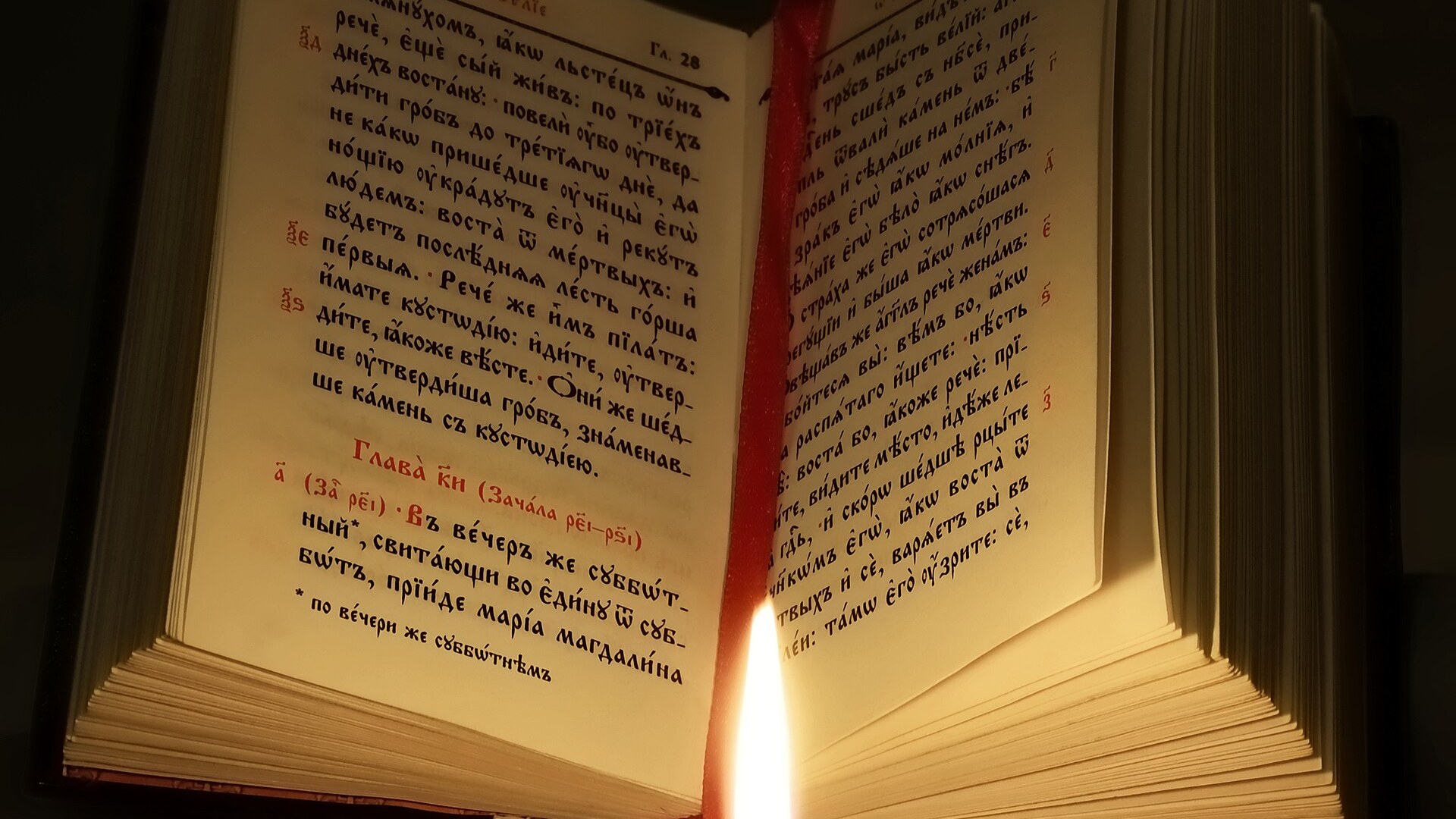 An open liturgical Gospel book lit by candlelight