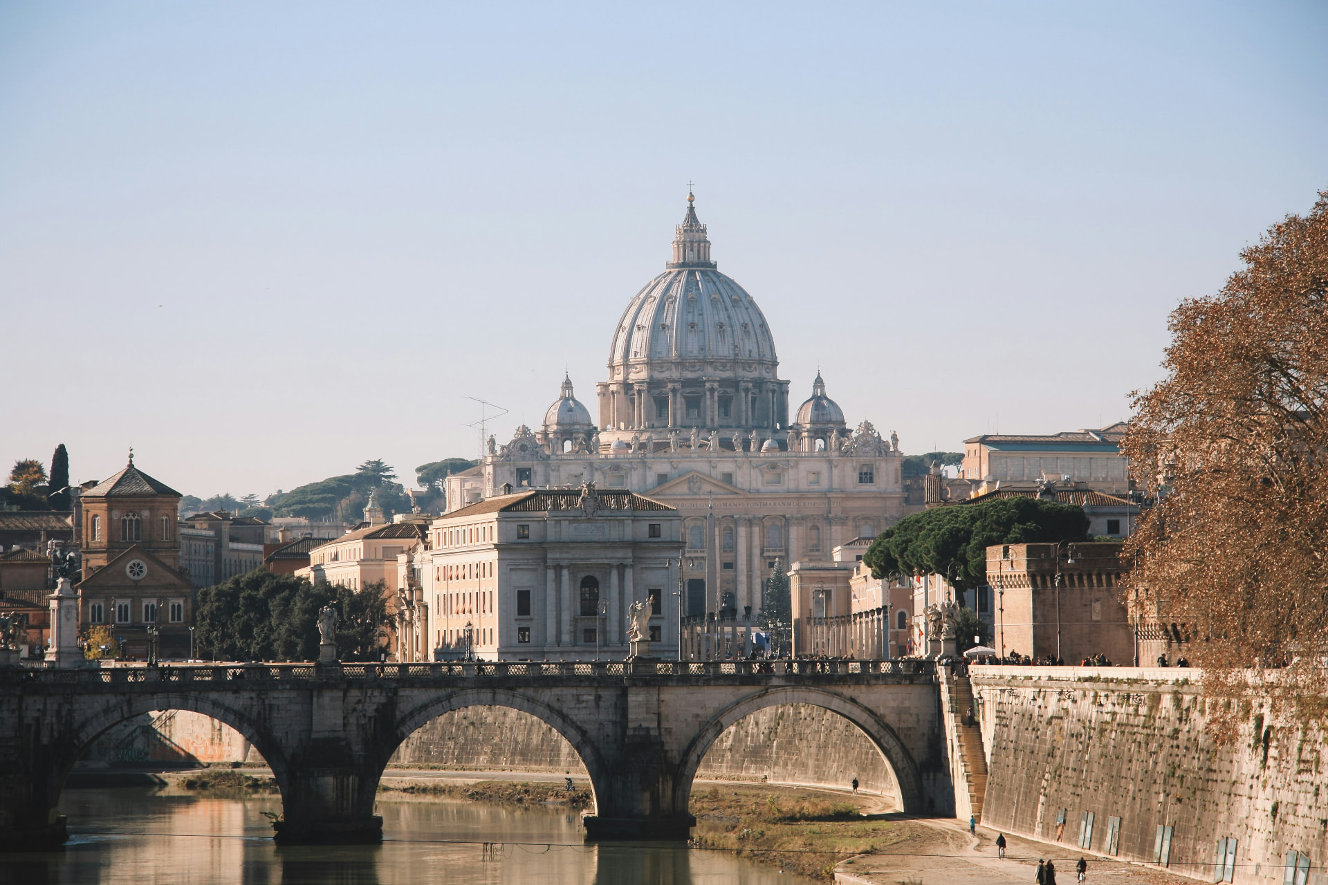 St. Peter's Basilica in Rome above the Tiber River and a stone bridge